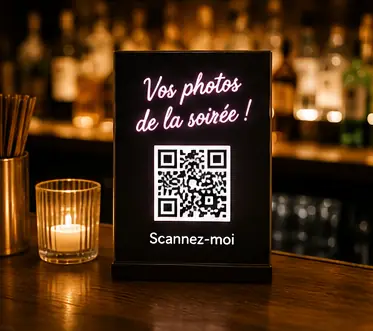 Chevalet lumineux avec QR code posé sur le comptoir d'un bar en soirée